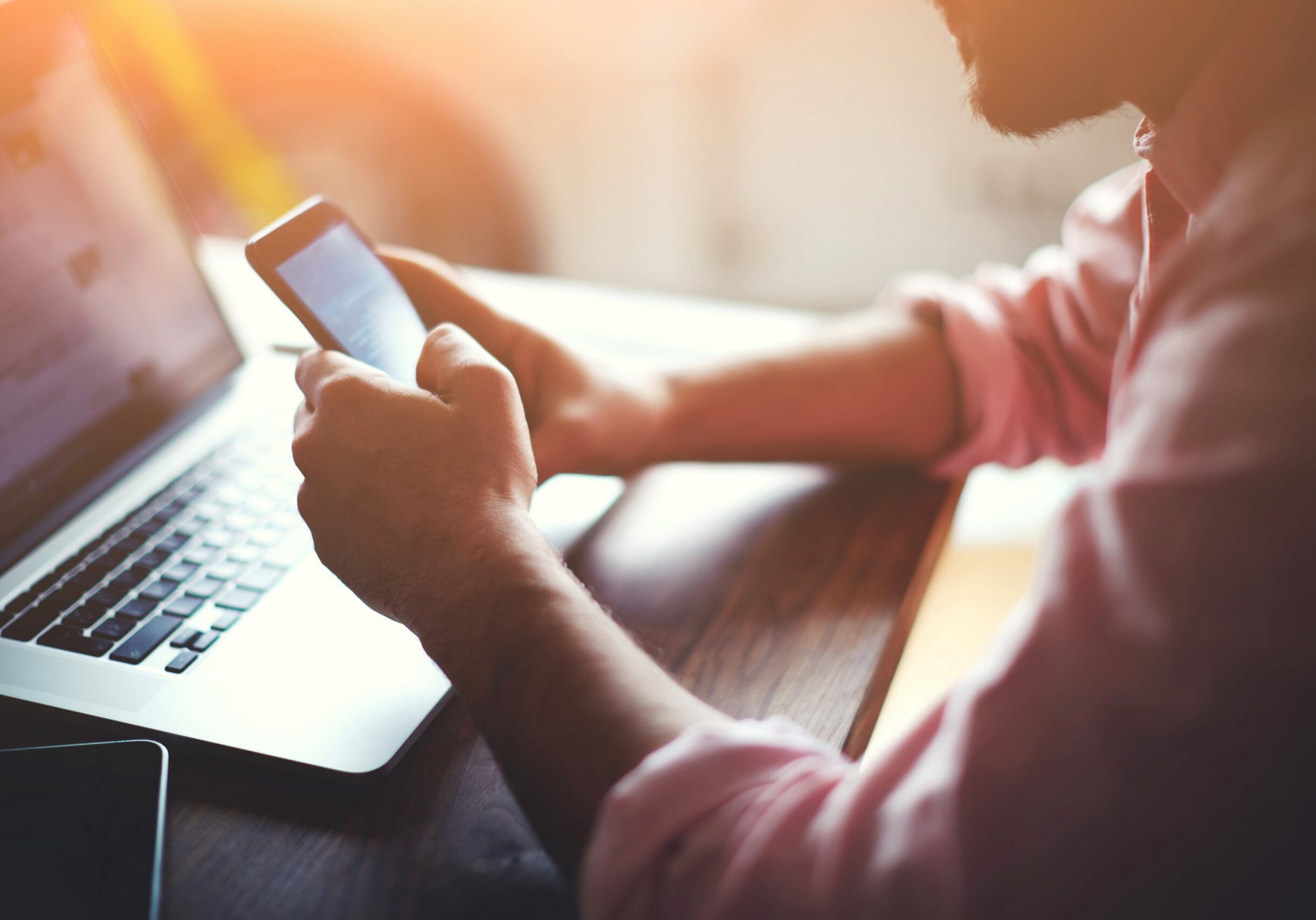 man working from home using smart phone and notebook computer